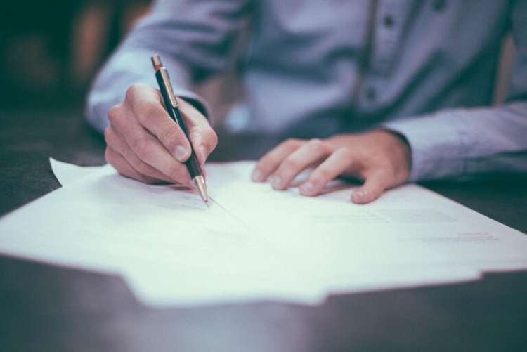 Person sitting at a desk writing on documents