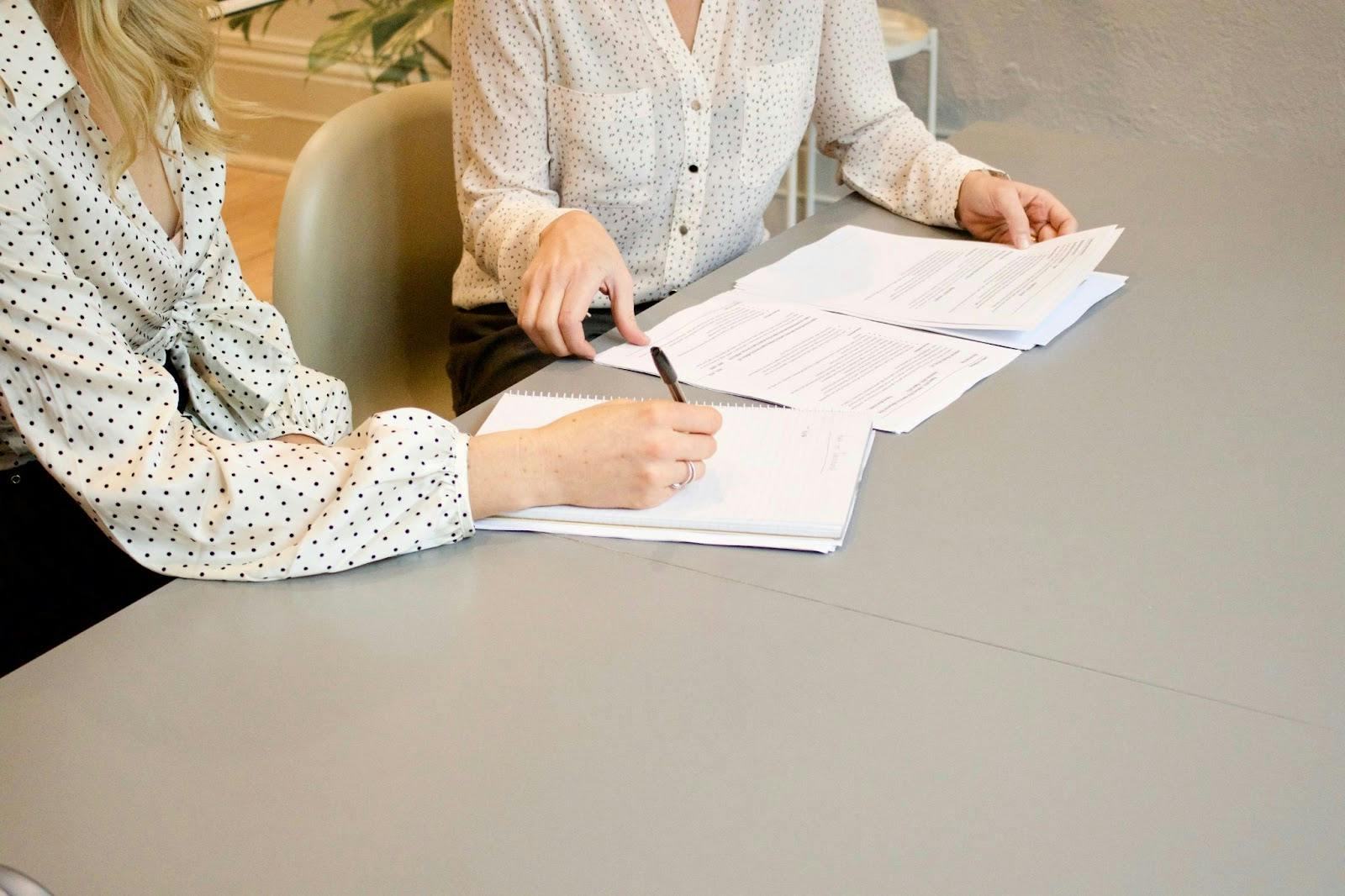 Two people sitting, signing documents together